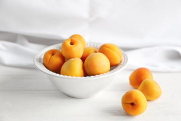 Heap of apricots in white plate on table