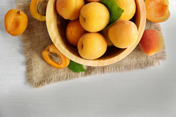 Heap of apricots in wooden bowl on table
