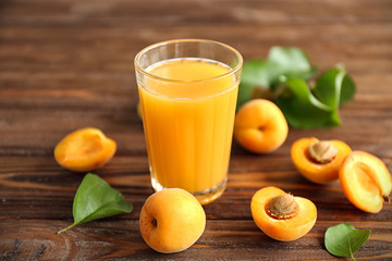Juice and few apricots on wooden table