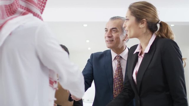  Smiling Western & Arab business people meeting & shaking hands in office
