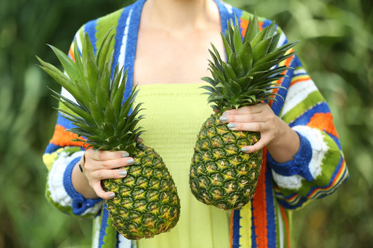 Woman holding pineapples on blurred nature background