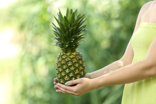 Woman holding pineapple on blurred nature background