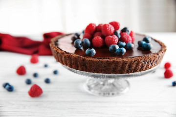 Delicious chocolate tart with berries on white table