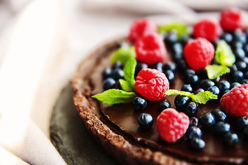 Delicious chocolate tart with berries on slate plate, closeup