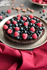 Delicious chocolate tart with berries on plate, closeup