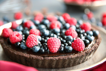 Delicious chocolate tart with berries on plate, closeup