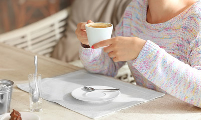 Woman hands holding cup of coffee in cafe