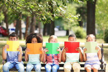 Cute kids reading books on bench