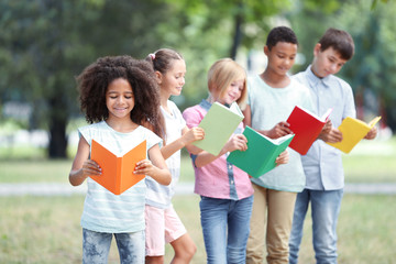 Cute kids reading books in park