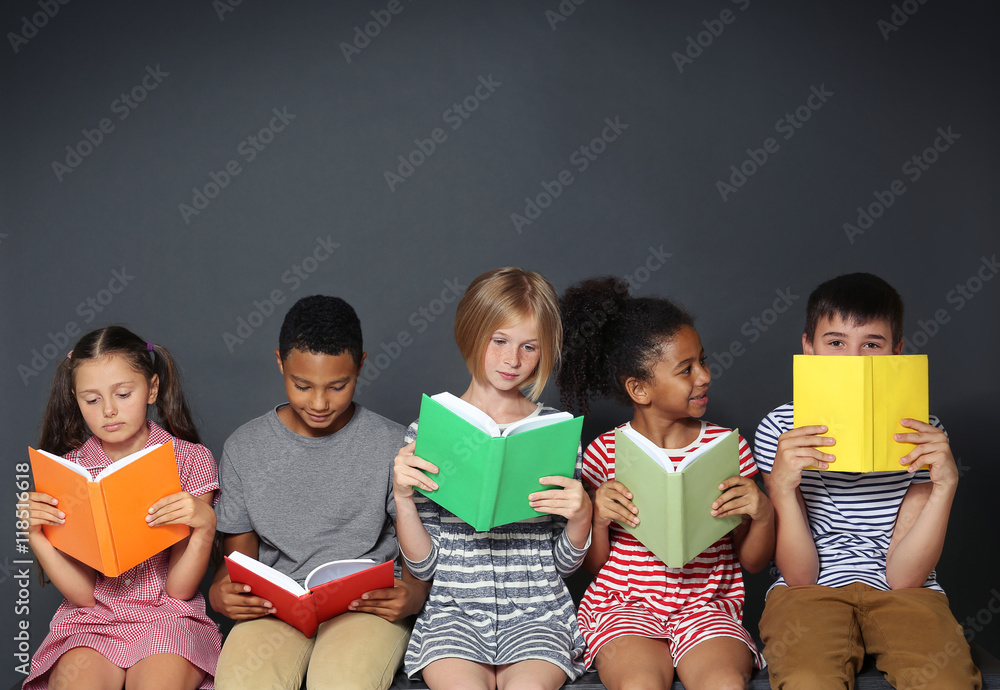 Wall mural Cute kids reading books on grey background