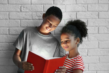 Cute kids reading book with flashlight