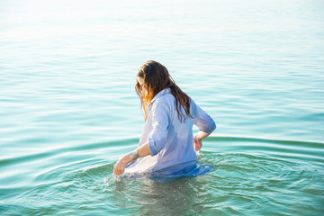 Fototapeta na wymiar woman on sea get into the water in wet shirt
