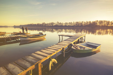 Marina on the lake, boats moored to a wooden pier, retro colors