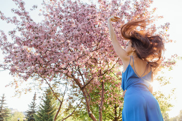 Beautiful young woman standing near the apple tree.