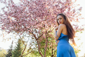 Beautiful young woman standing near the apple tree.