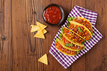 Tacos with meat and vegetables on wooden board