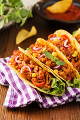 Tacos with meat and vegetables on wooden board