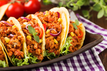 Tacos with meat and vegetables on wooden board