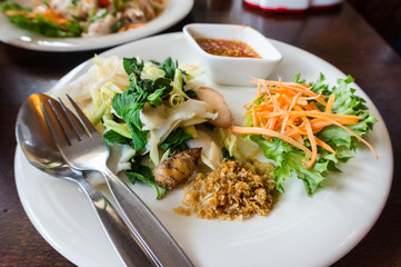 Boiled fish sauce with Ginger, carrot, lettuce, galangal, basil, lemon grass on white dish