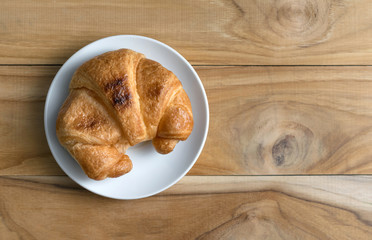 Fresh baked croissants on wood table from above