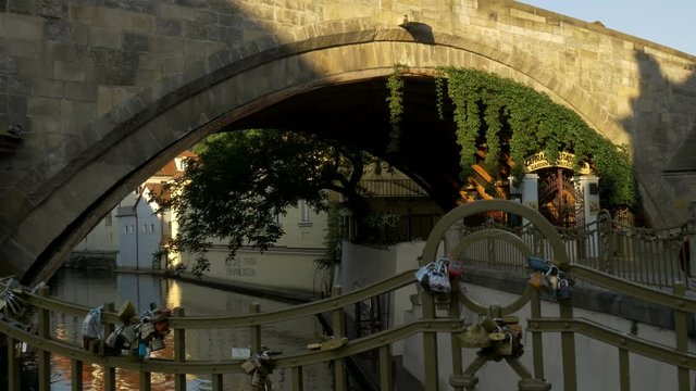 Pan shot from love locks on railings to the west tower of Charles Bridge in Prague. Taken from Certovka 