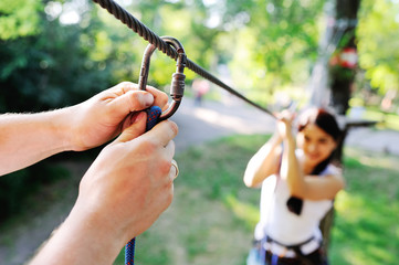 man climbing carabiner mount on background asian girl in the ropes course