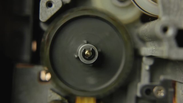 Inside a super 8mm film projector: a big wheel spinning fast. Macro detail shot.
