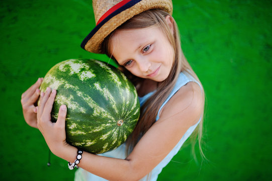 little girl in a straw hat with watermelon in his hands on a green background