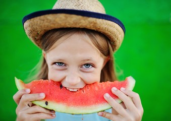 baby girl greedily eating ripe watermelon on a green background