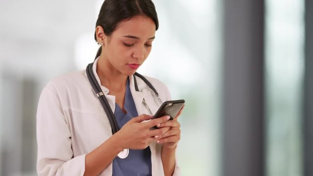 Latina doctor texting on smartphone