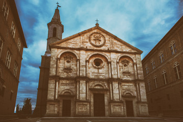 Fototapeta na wymiar Twilight view of the Pienza Assumption of the Virgin Mary Cathedral with dark blue sky. Facade from white marble. Religious travel destinations background.