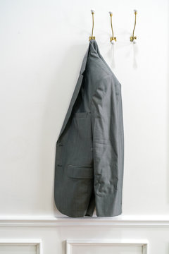 Man's jacket hanging on a coat hanger at a wall
