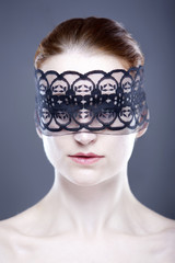 Junge Frau mit einer Maske aus schwarzer Spitze