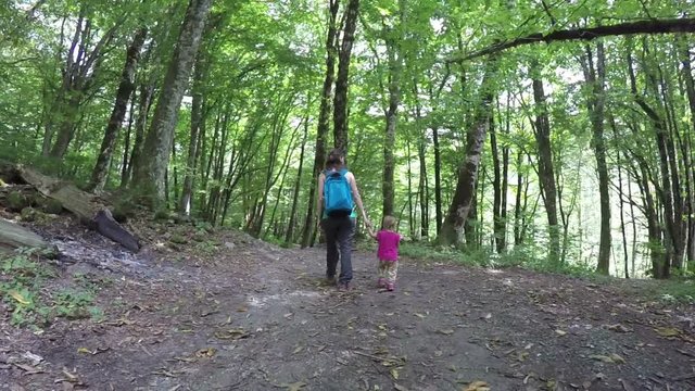 Mom walks her daughters hand with a pink backpack in the woods. Healthy lifestyle. Family walk in the woods outdoors. Full HD. 1920x1080