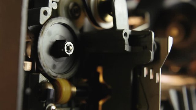 Inside a super 8mm film projector: a spinning wheel. Macro detail angled shot.
