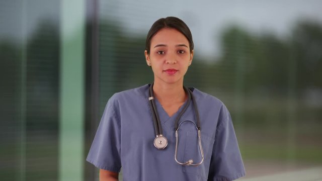 Young Mexican woman intern at hospital standing in hallway