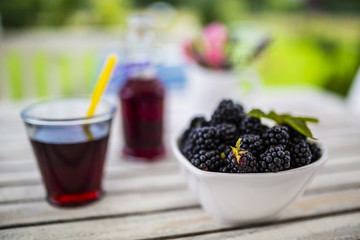 Fototapeta na wymiar Fresh blackberries in bowl on wooden table in the garden