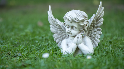 Engel Figur im Gras als Hintergrund oder Karte für Trauer, Tod oder Kondolenz und Schutzengel