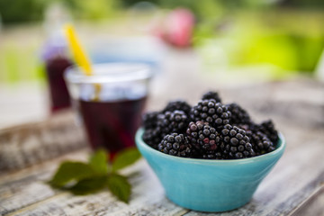 Fresh blackberries in bowl on wooden table in the garden