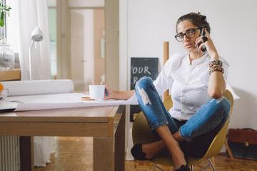 Fototapeta premium Woman talking on the phone in her home office.