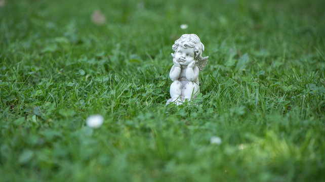 Engel Figur im Gras als Hintergrund oder Karte f&uuml;r Trauer, Tod oder Kondolenz und Schutzengel