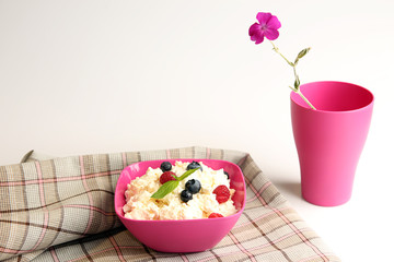 Cottage cheese in pink plastic bowl decorated mint and berry.