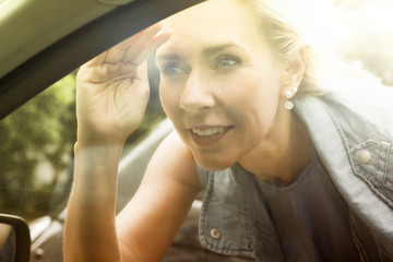 blond woman is looking inside a car