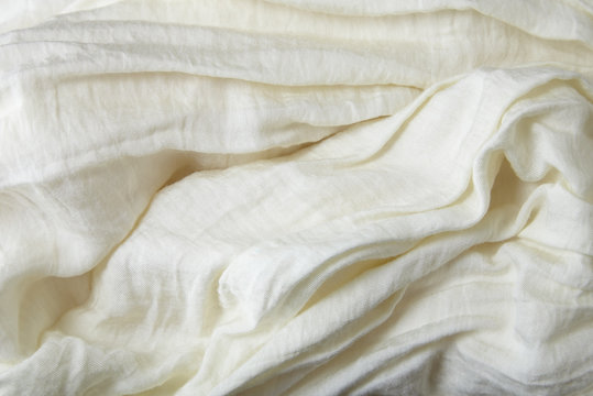 A full page close up of creased cream colored crepe fabric texture