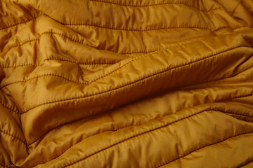 A full page close up of yellow quilted sleeping bag fabric texture