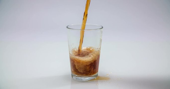 Someone is pouring a diet coke into an empty glass until it is completely full. A drink is standing on a table. Close-up shot.
