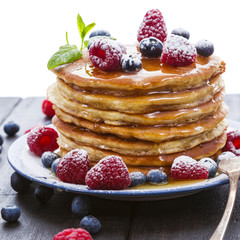 Pancakes with honey and berries on white background