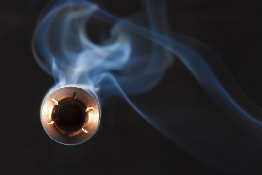 Hollow point bullet coming directly at the camera on a dark background with smoke behind