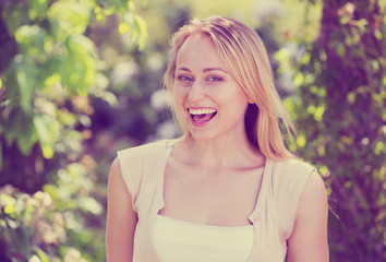 Fototapeta premium Portrait of glad young blond woman in garden