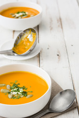 Pumpkin soup in bowl on a white wooden table

